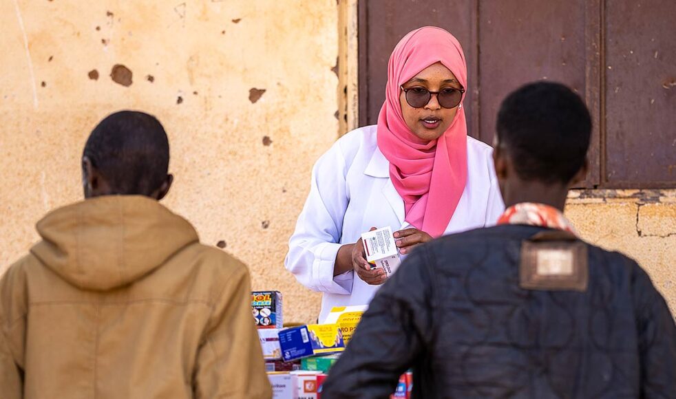 Sjuksköterskan Noura Awil instruerar en ung man hur han ska ta sin antibiotika.
