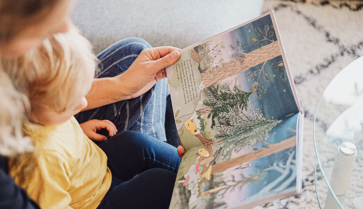 Sonen Olle lyssnar spänt när mamma Amanda högläser ur barnboken I en helt vanlig skog.