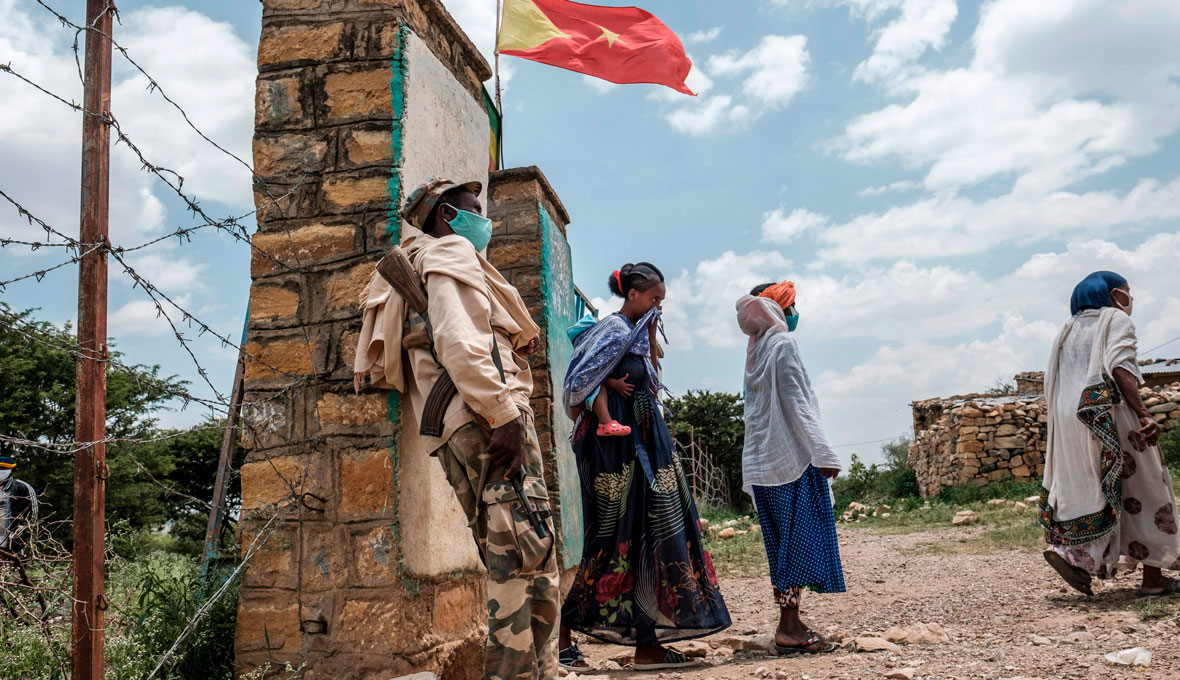 En beväpnad vakt utanför en av vallokalerna under det osanktionerade val som hölls i Tigray-regionen i september. Ovanför vajar regionens fana. Bild: TT